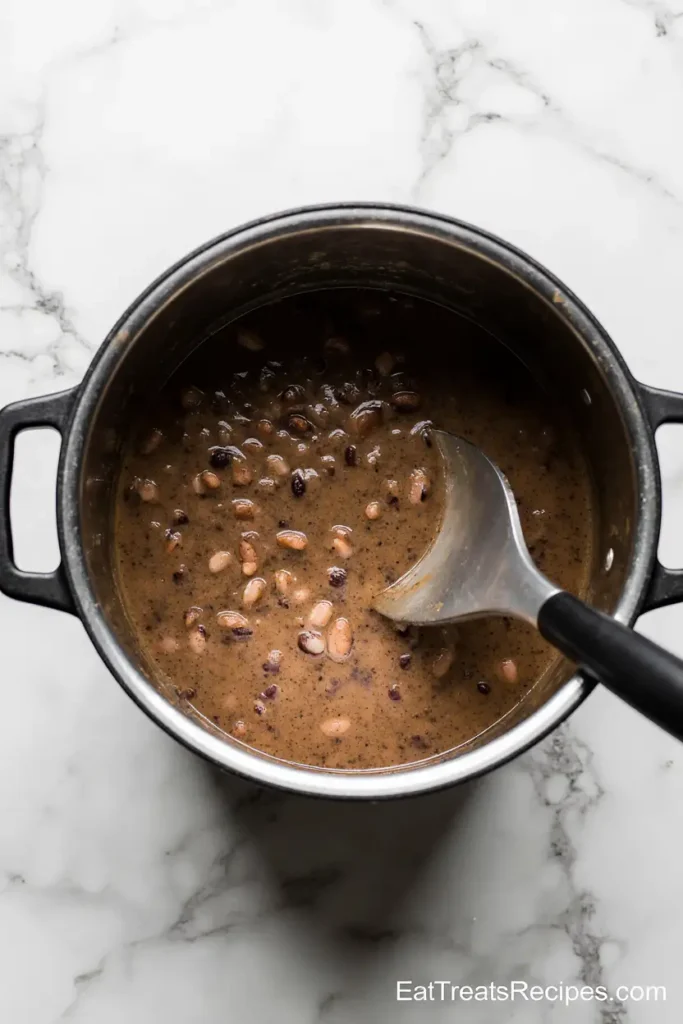 Immersion blender blending black bean soup in pot