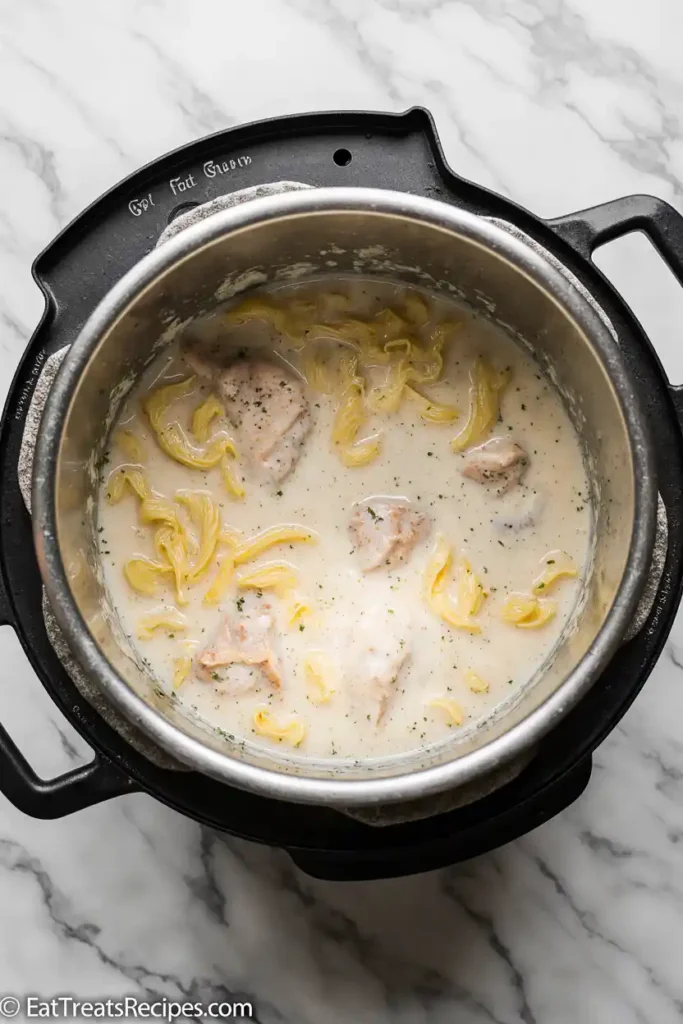 Pot with noodles, chicken, cream, and cheese simmering
