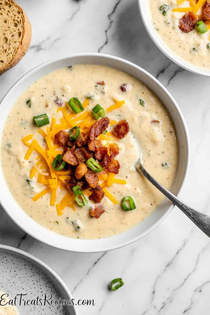 Finished creamy potato soup with cheese, bacon, and chives served in a white bowl