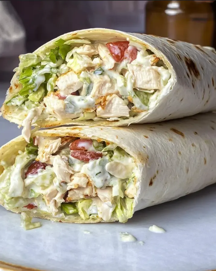 Chopped chicken Caesar salad wrap sliced open on white marble
