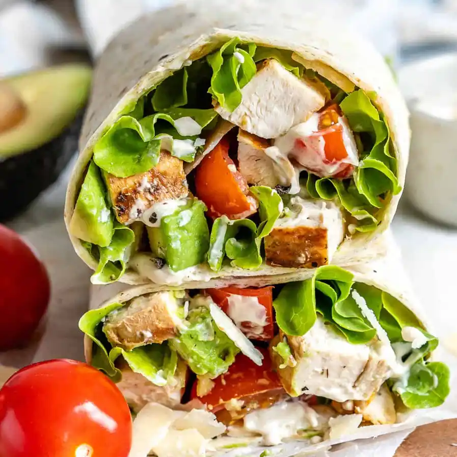 Chopped chicken Caesar salad wrap sliced open on white marble