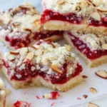 Modern Christmas cheesecake bars with vibrant cranberry swirl on white marble
