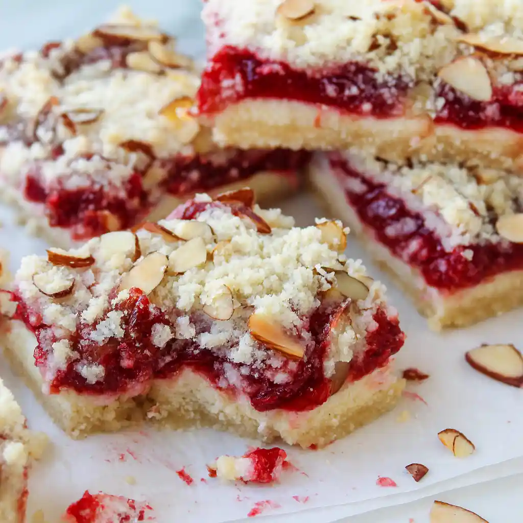 Modern Christmas cheesecake bars with vibrant cranberry swirl on white marble