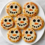 Christmas mini snowman pizzas on white marble with festive décor.