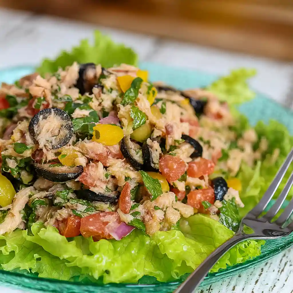 Close-up of tuna flakes, olives, tomatoes and herbs in Italian tuna salad