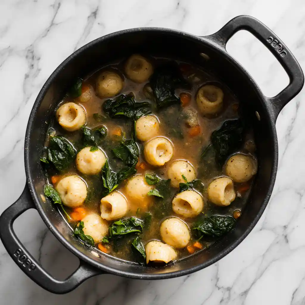 Pot of vegetable tortellini soup simmering with spinach and pasta