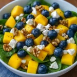 Mango salad with spinach and blueberries in a cozy serving bowl