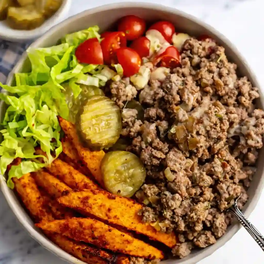 Cozy High-Protein Cheeseburger Bowls with beef, cheese, and fresh toppings on white marble background