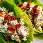 Chicken bacon ranch lettuce wraps ingredients including shredded chicken, crispy bacon, ranch dressing, cheese and romaine lettuce on white marble background