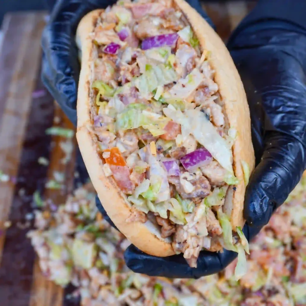 toasted chopped chicken bacon ranch sandwich cut in half showing creamy filling on marble surface