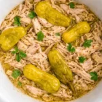 A cozy bowl of Crockpot Mississippi Chicken featuring shredded chicken, buttery sauce, and pepperoncini peppers.