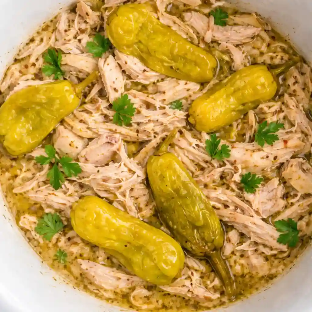 A cozy bowl of Crockpot Mississippi Chicken featuring shredded chicken, buttery sauce, and pepperoncini peppers.