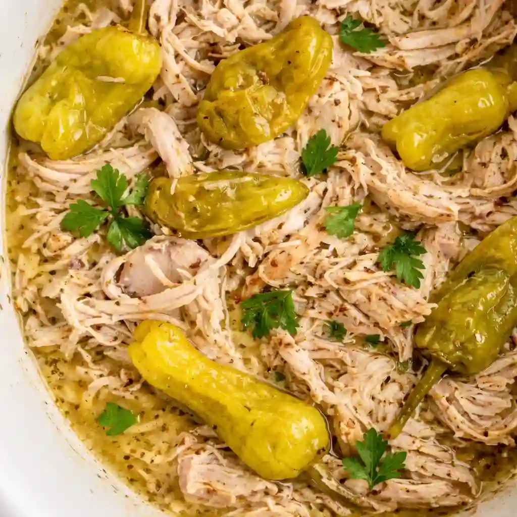 A cozy bowl of Crockpot Mississippi Chicken featuring shredded chicken, buttery sauce, and pepperoncini peppers.