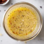 Homemade parmesan vinaigrette in glass jar on white marble surface