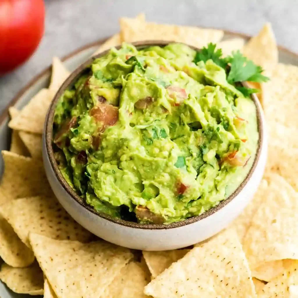 Serving authentic guacamole recipe with tortilla chips in white bowl