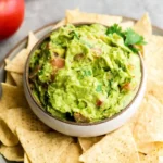 Serving authentic guacamole recipe with tortilla chips in white bowl