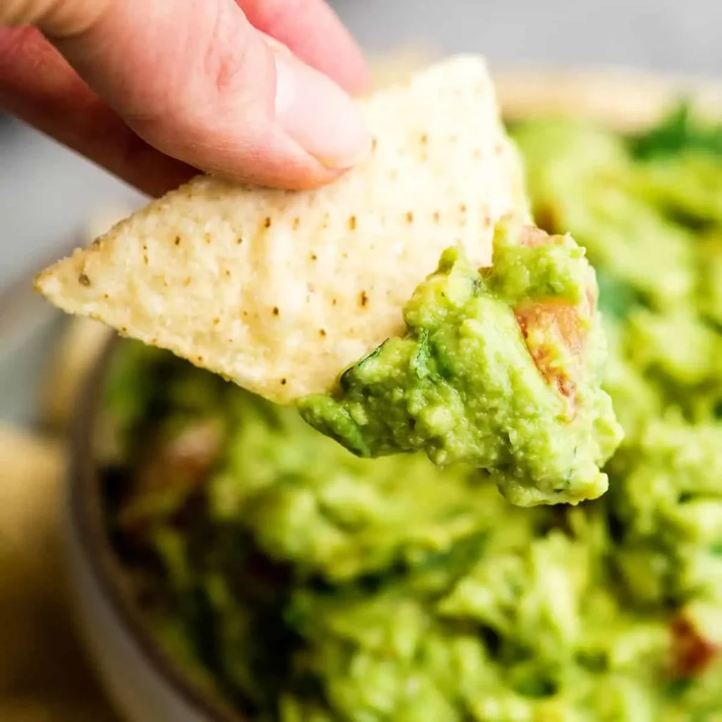 Serving authentic guacamole recipe with tortilla chips in white bowl