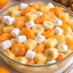 Sunshine Salad with mandarin oranges, pineapple and marshmallows in white bowl on marble surface