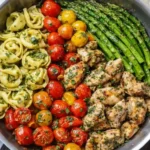 Pesto chicken tortellini and veggies served in skillet with basil pesto sauce and colorful vegetables